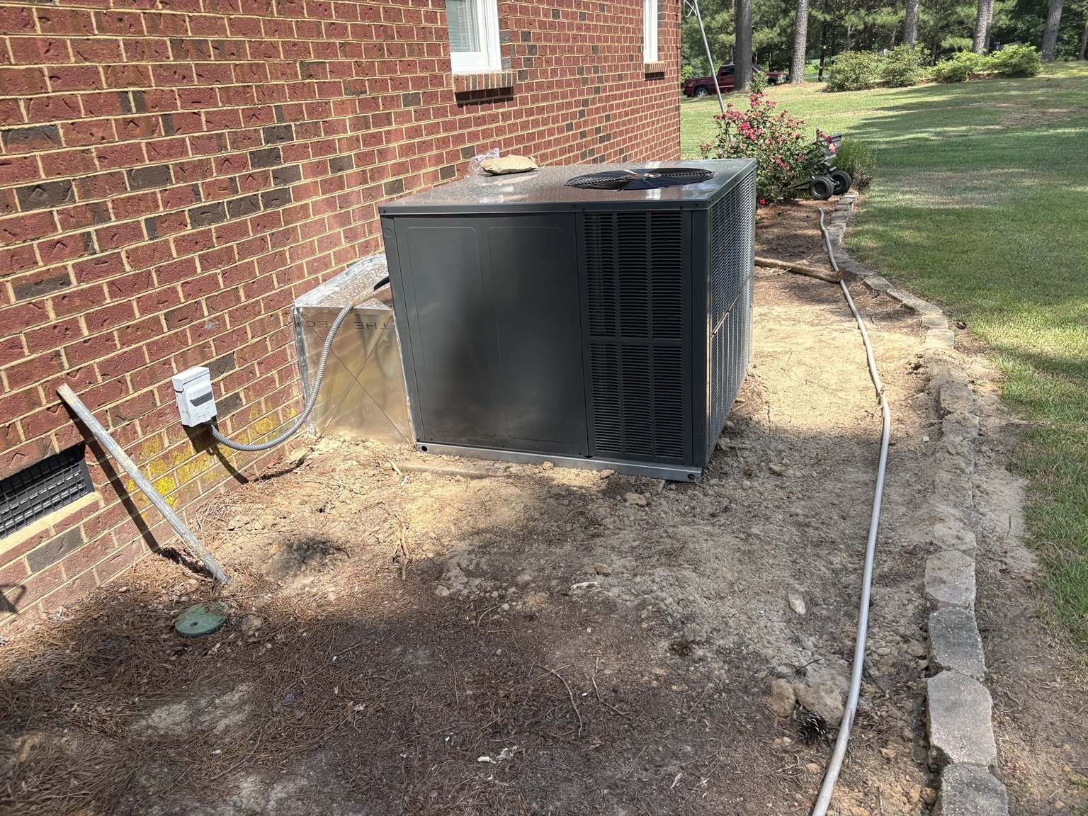 New packaged HVAC system installed beside a brick home